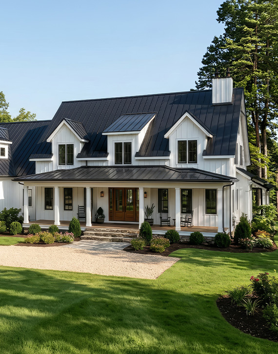 property-slider-Cottage Lots Front exterior of a two-story modern farmhouse with white vertical siding, a black standing-seam metal roof, black-trimmed dormers, a covered front porch with a wood entry door and rocking chairs, and a well-maintained lawn and landscaping.